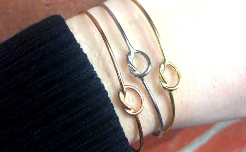 white gold, yellow gold, and rose gold love knot bracelets on a wrist